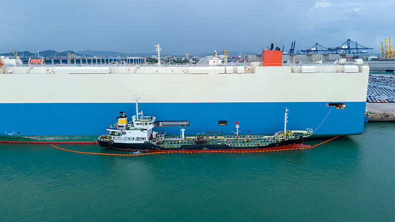 Oil ship refuelling a cargo ship at dock, refuelling at port