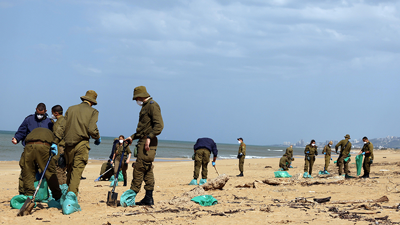  Israeli soldiers clean tar from a beach in Atlit, Israel on February 22, 2021