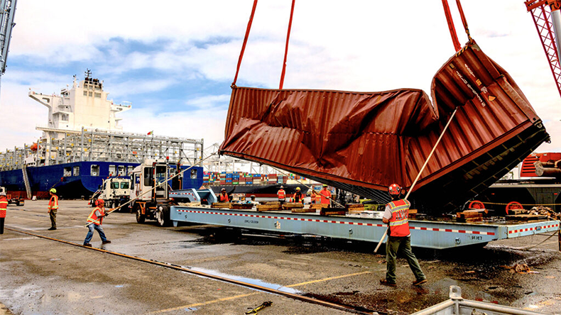 A damaged container, retrieved from the water, is loaded on to a trailer for removal
