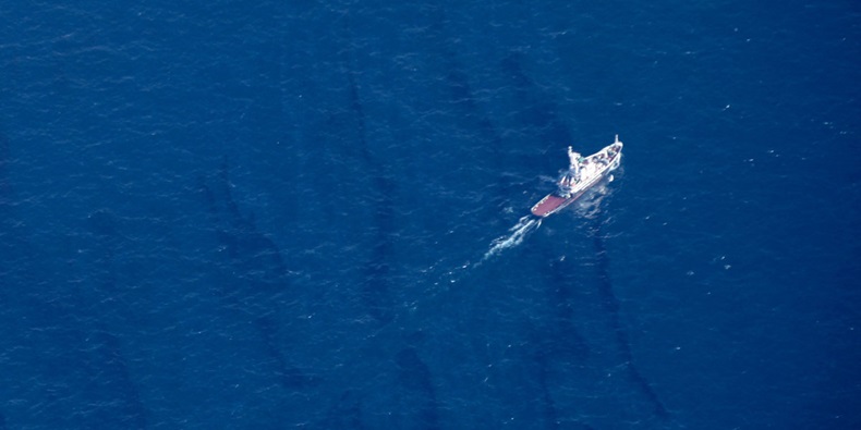 Ship moving through Sanchi oil slick