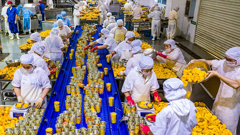 Factory workers process peaches at a plant in Yihang in 2021