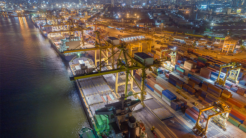 Logistics and transport of containers from cargoships with working crane bridge in shipyard at sunrise, logistic import export