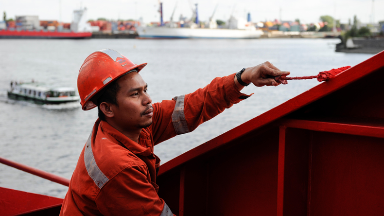 Filipino seafarer painting on a ship in port