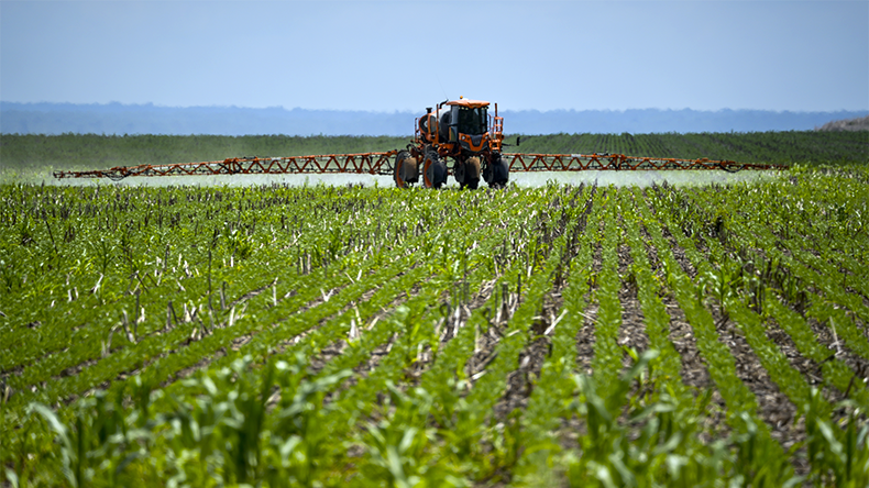 Tractor spraying agricultural pesticides, fertilisers, and seeds in a soyabean plantation on a farm in the Amazon, Mato Grosso, Brazil