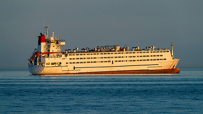 Large livestock carrier ship sailing on sea at sunset