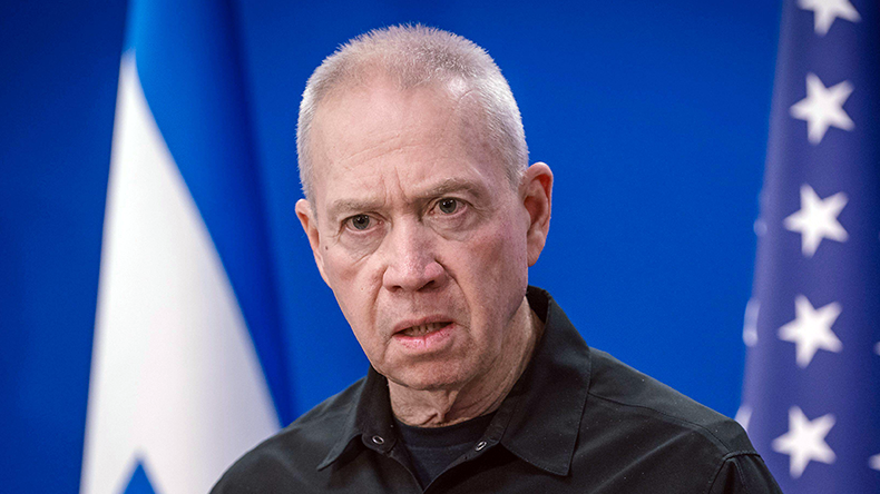Israeli Defence Minister Yoav Gallant with Israel and US flags behind him