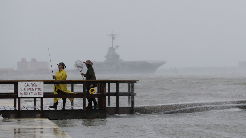 Fishermen walk along a pier as the early bands of Hurricane Harvey make landfall, Friday, Aug. 25, 2017, in Corpus Christi, Texas. Harvey intensified into a hurricane Thursday and steered for the Texas coast with the potential for up to 3 feet of rain, 125 mph winds and 12-foot storm surges in what could be the fiercest hurricane to hit the United States in almost a dozen years.