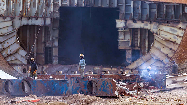 Worker wearing red safety helmet working on the wreck of ship at Gadani Ship Breaking Yard
