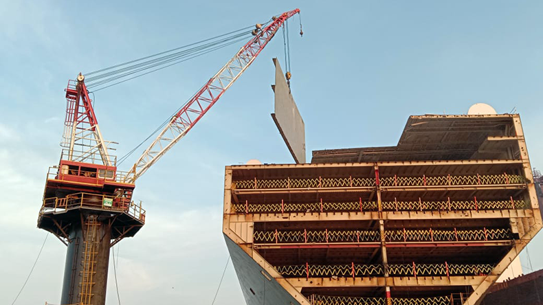 Removing steel plates from ship using cranes in ship recycling yard in Alang, India