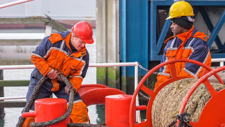 Deck officer working with ropes together with crew