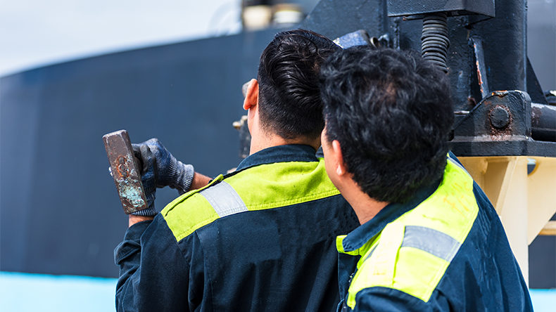Two ship engineers focused on deck equipment repairs