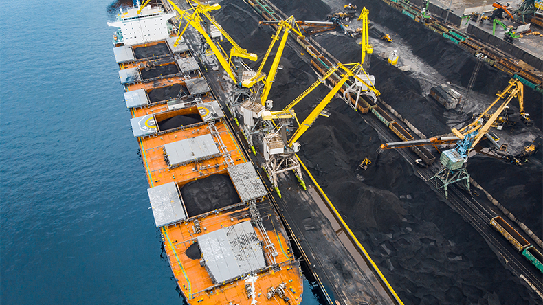 Loading coal anthracite mining in port on cargoship with crane bucket