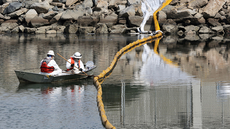 Workers collect oil from sea at Huntington Beach, California, October 4, 2021