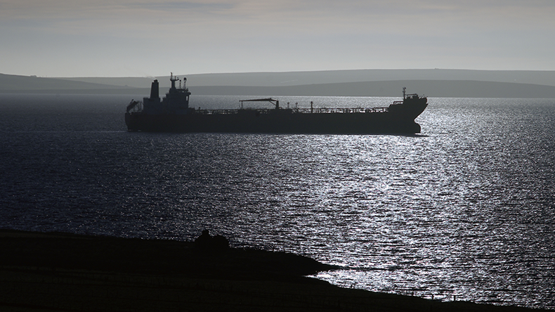 Oil tanker ship at anchor dawn with sunlit silhouette