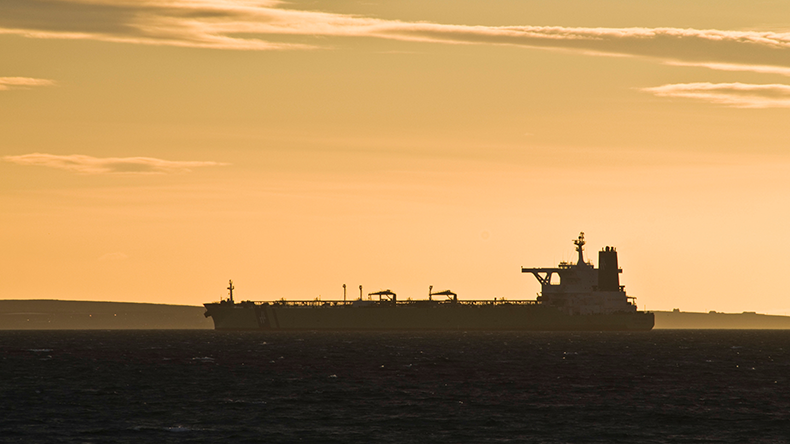 Oil tanker at sunset in silhouette anchored at sea 