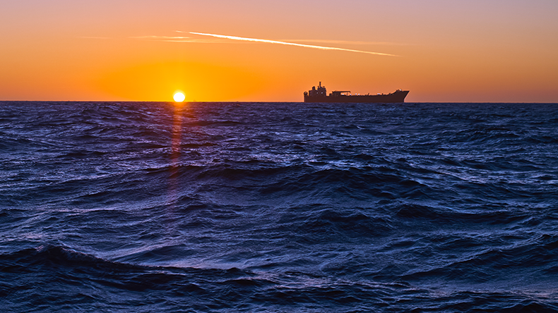 Tanker on horizon with sun setting