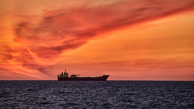 Beautiful ocean sunset , with colourful red and orange sky, dark sea and silhouette of ship on the horizon