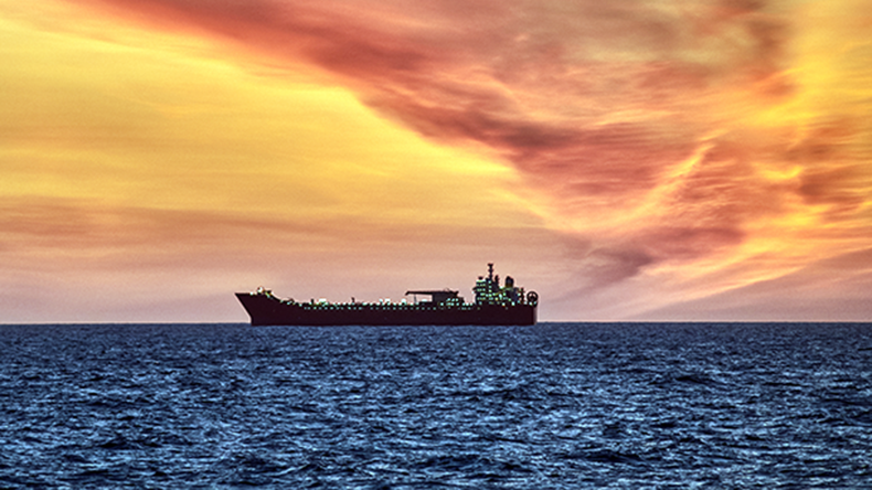 Beautiful ocean sunset , with colourful red and orange sky, dark sea and silhouette of ship on the horizon