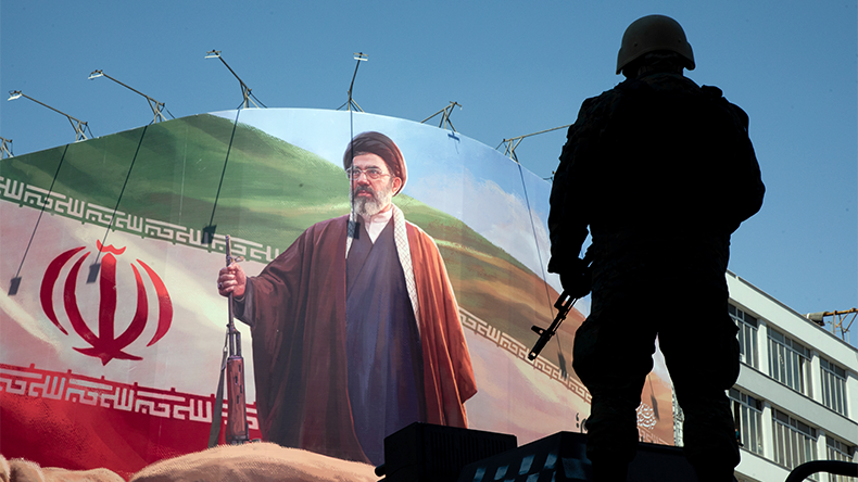 A member of the Iranian security forces stands guard under a large portrait of Iran's new Supreme Leader, Mojtaba Khamenei in Tehran, Iran