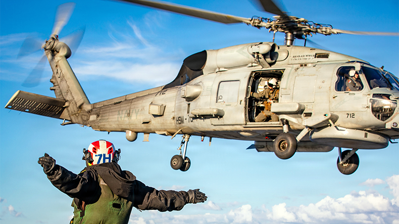 U.S. Sailor signals the launch of an MH-60R Sea Hawk helicopter, attached to Helicopter Maritime Strike Squadron 70, on the flight deck of the world's largest aircraft carrier, USS Gerald R. Ford (CVN 78)