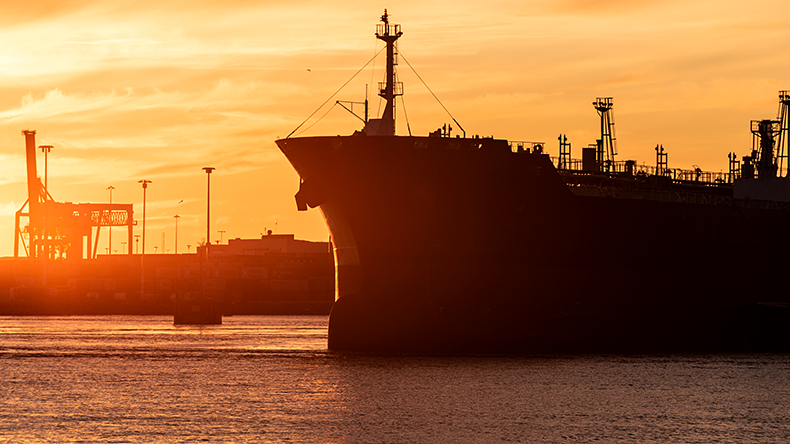 Dark fleet tanker leaving port at sunset 