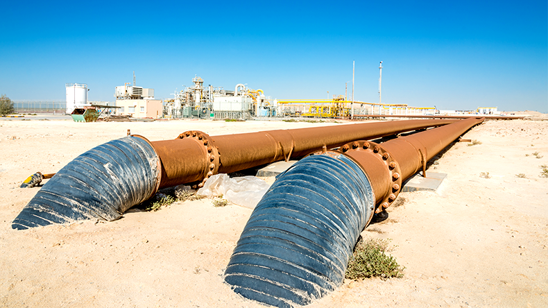 Oil industry pipelines from oil refinery Complex leading into desert sand Saudi Arabia
