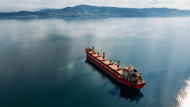Bulk carrier approaching port on a clear blue still ocean with a sunny sky